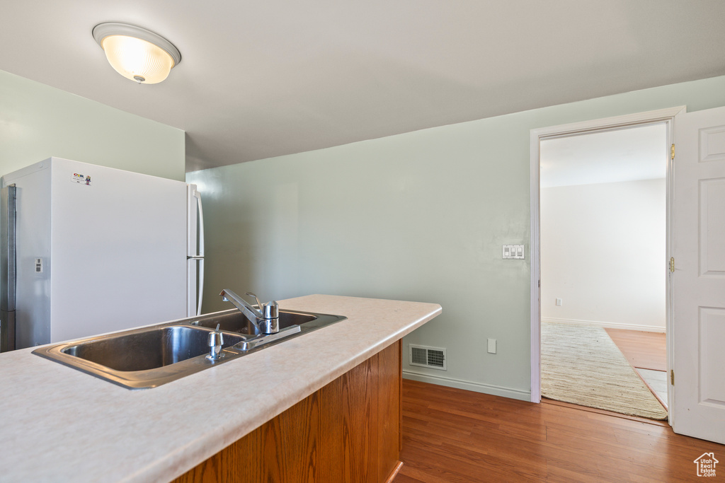 Kitchen featuring freestanding refrigerator, wood finished floors, and light countertops