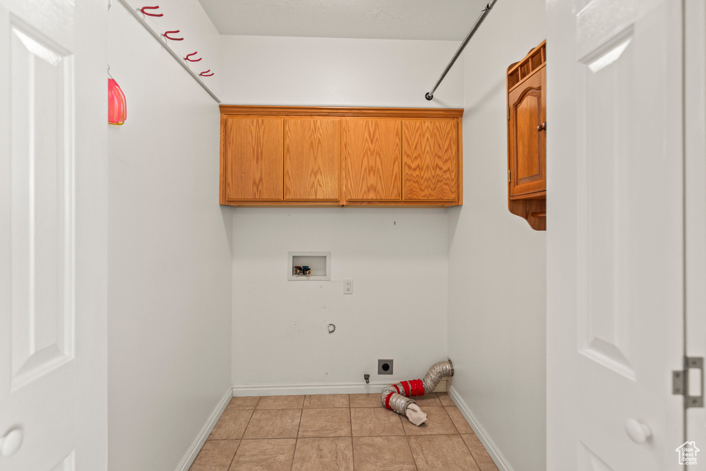 Washroom with cabinet space, washer hookup, electric dryer hookup, gas dryer hookup, and light tile patterned flooring