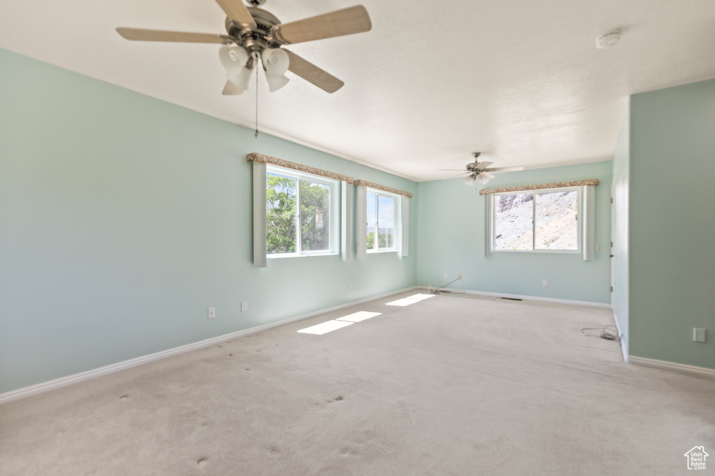Empty room with carpet, ceiling fan, and a smoke detector