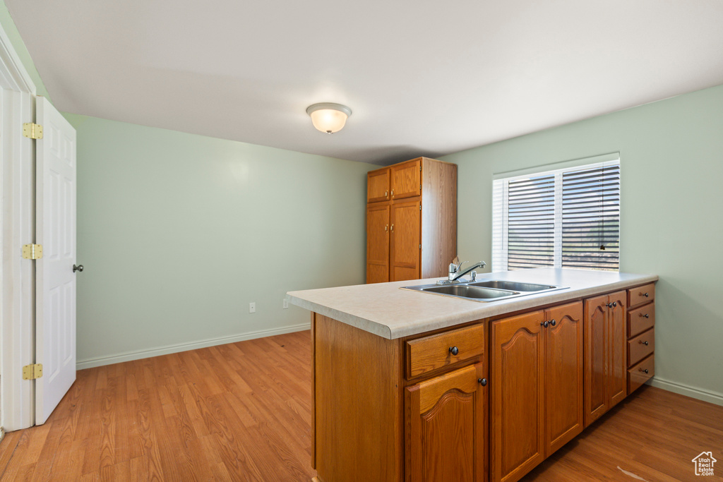 Kitchen featuring light wood-type flooring, light countertops, brown cabinetry, and a peninsula