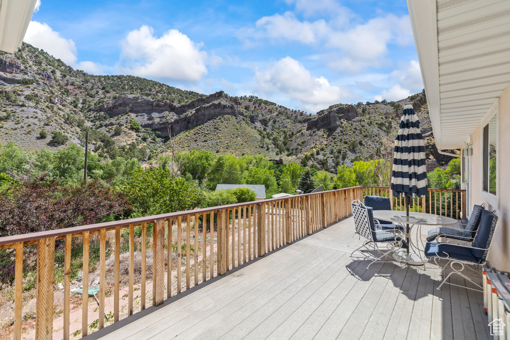 Wooden deck with outdoor dining space and a mountain view
