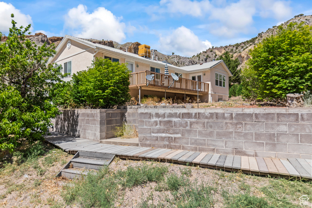 Back of house with a deck with mountain view and stucco siding