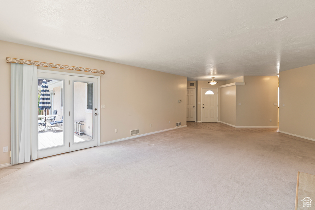Unfurnished living room with baseboards and light carpet
