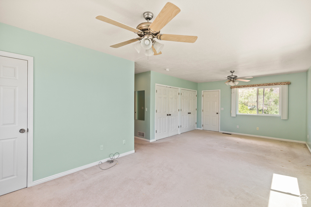 Unfurnished bedroom with multiple closets, carpet, ceiling fan, and electric panel