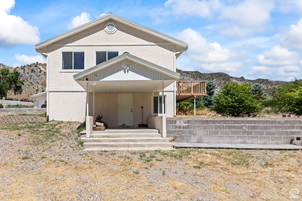 View of front of property with stucco siding and a deck with mountain view