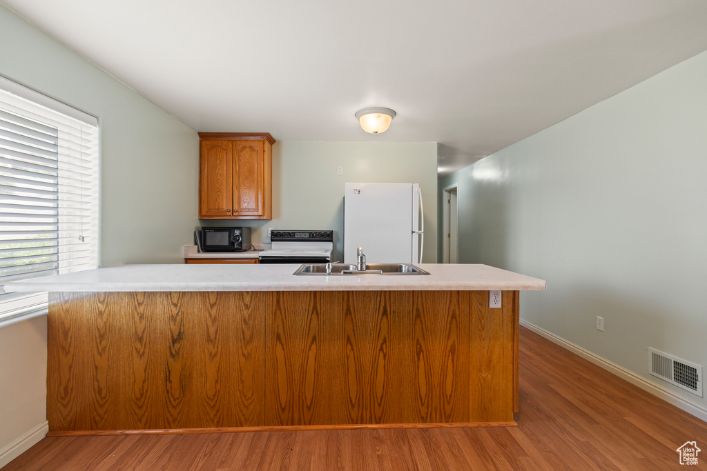 Kitchen featuring freestanding refrigerator, range with electric stovetop, light wood finished floors, light countertops, and black microwave