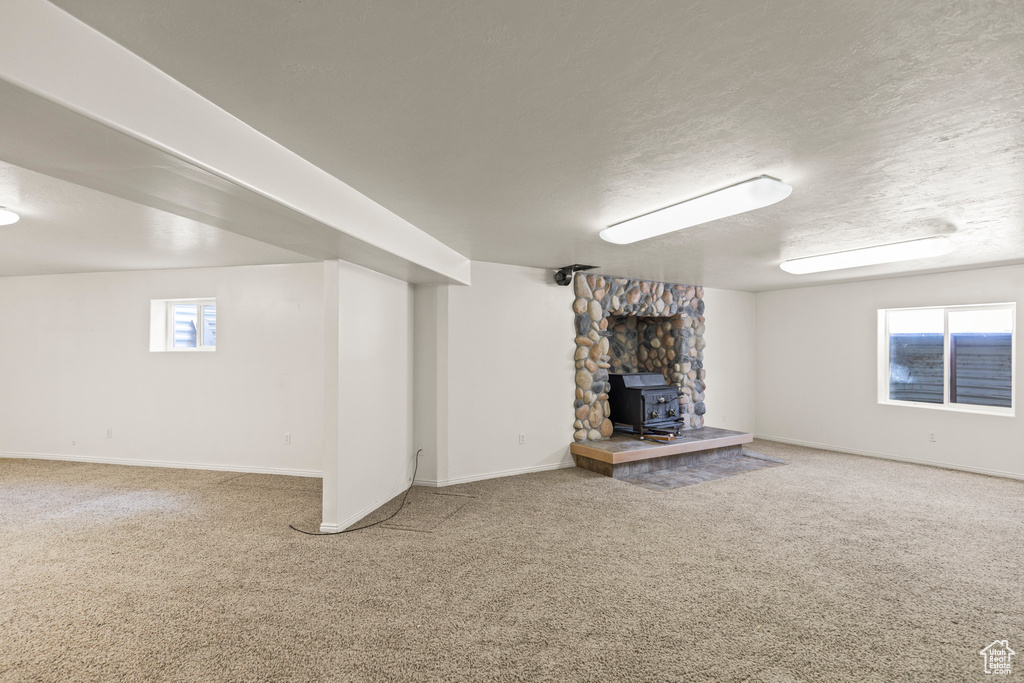 Below grade area with a wood stove, carpet floors, and a textured ceiling