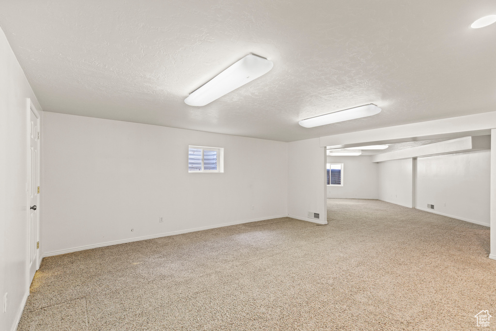 Below grade area featuring a textured ceiling, carpet, and plenty of natural light
