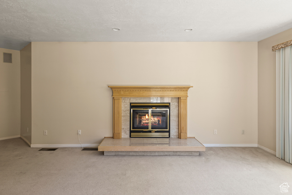 Detailed view of carpet floors, a premium fireplace, and a textured ceiling