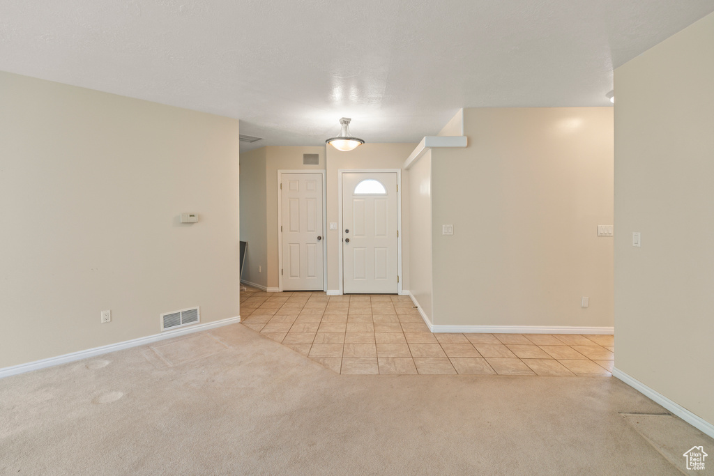 Foyer entrance with light carpet and light tile patterned flooring