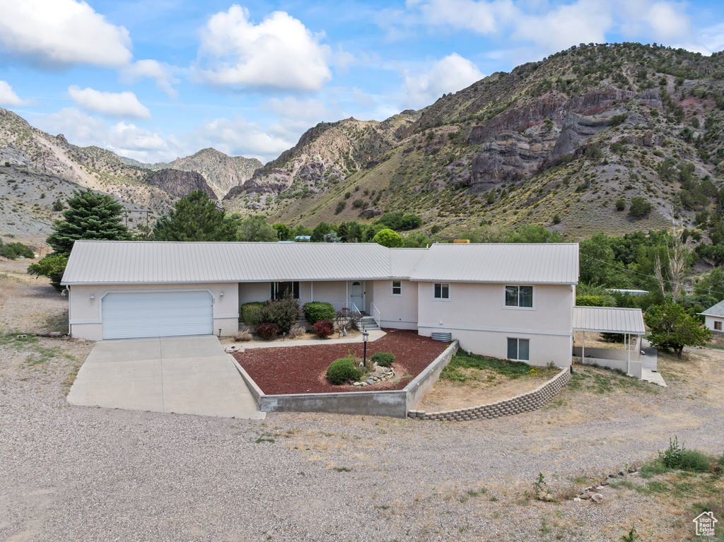 Single story home with concrete driveway, an attached garage, a metal roof, and a mountain view