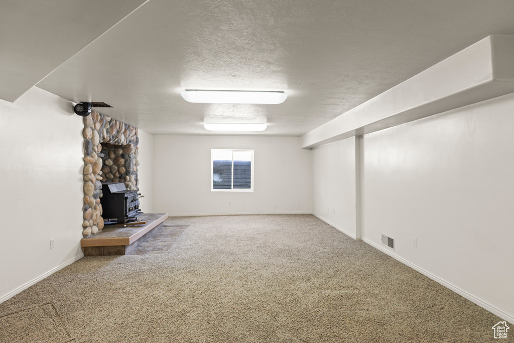 Unfurnished living room with a wood stove and carpet flooring
