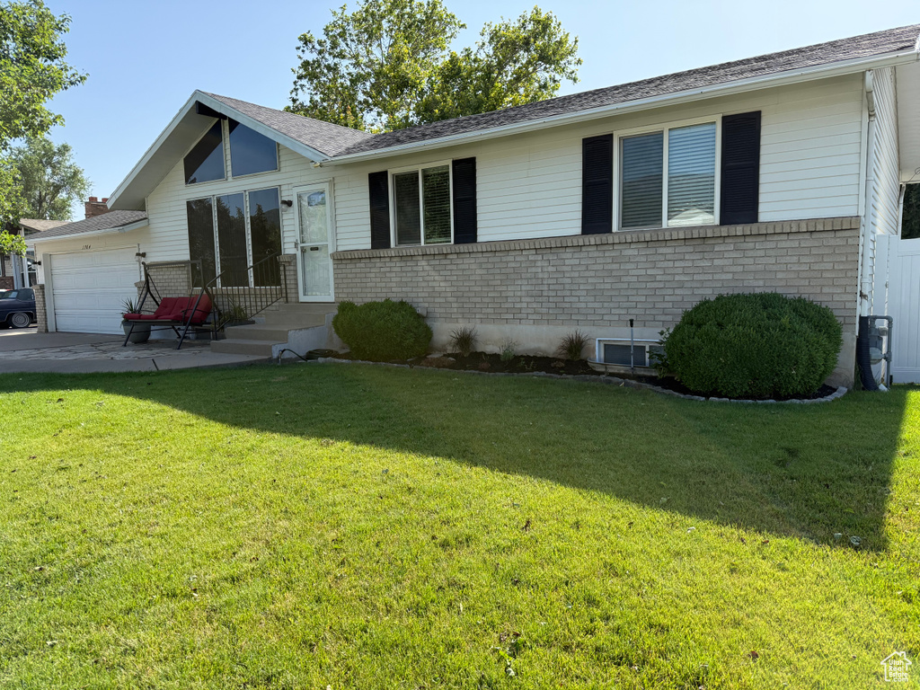 Ranch-style house with brick siding, a garage, a front lawn, and concrete driveway