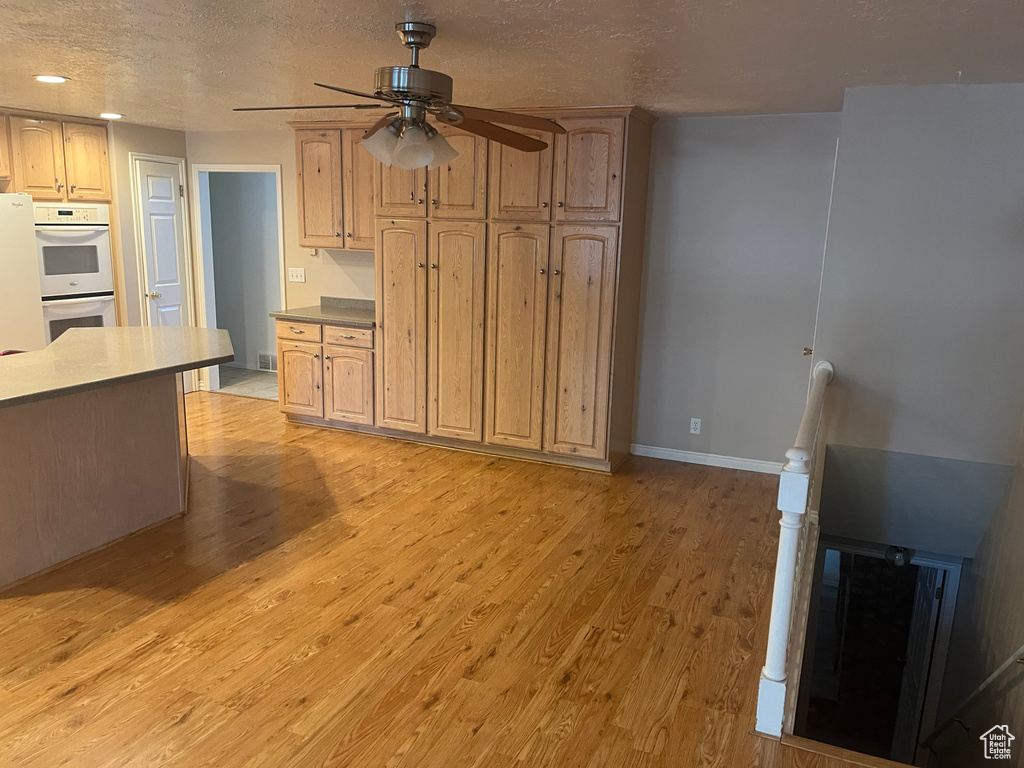 Kitchen with white appliances, ceiling fan, light wood-type flooring, recessed lighting, and a textured ceiling