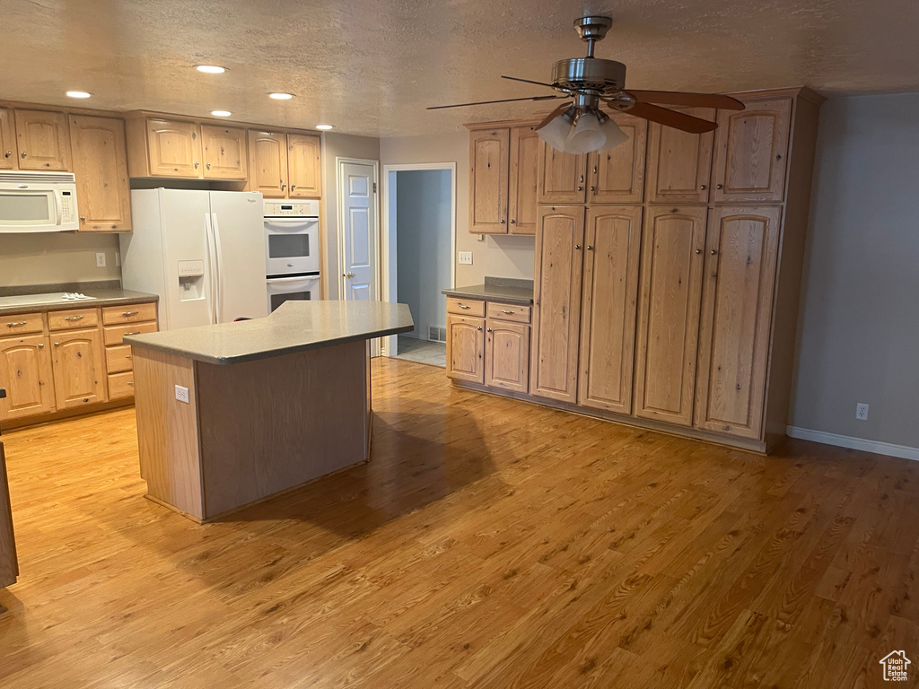 Kitchen featuring white appliances, recessed lighting, ceiling fan, a center island, and light wood-type flooring