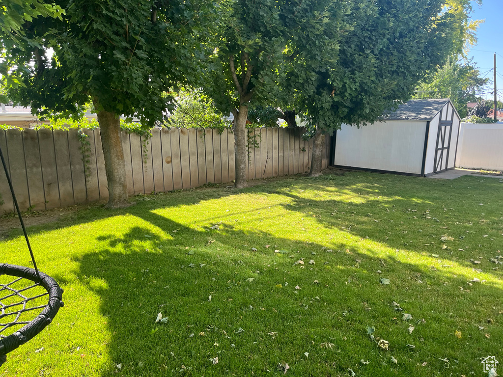 Fenced backyard featuring a storage shed