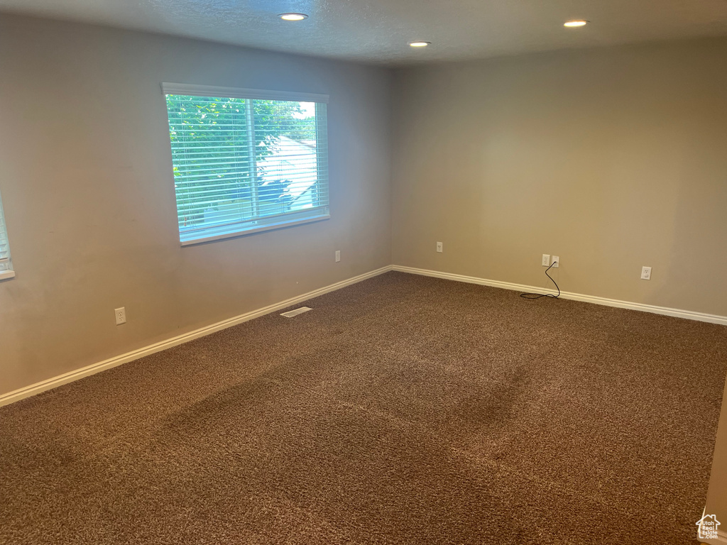Unfurnished room with dark colored carpet and recessed lighting