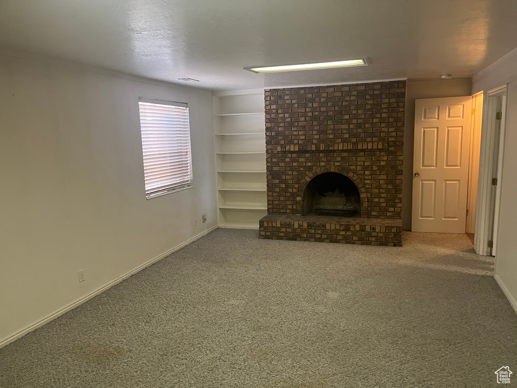Unfurnished living room featuring a brick fireplace, carpet, and built in features