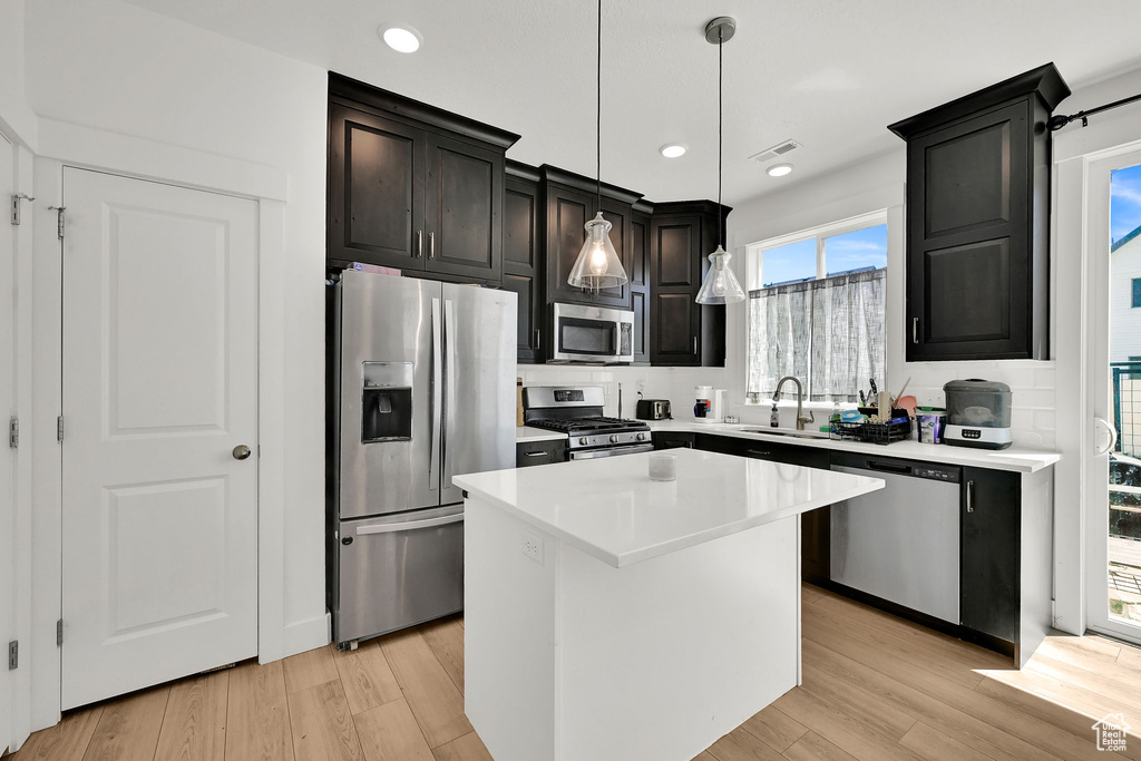 Kitchen with stainless steel appliances, a center island, light countertops, light wood-type flooring, and recessed lighting