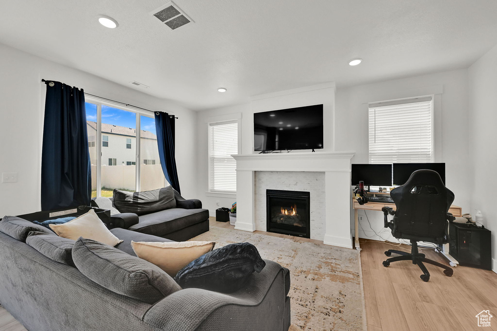 Living room featuring wood finished floors, a warm lit fireplace, an office area, and recessed lighting