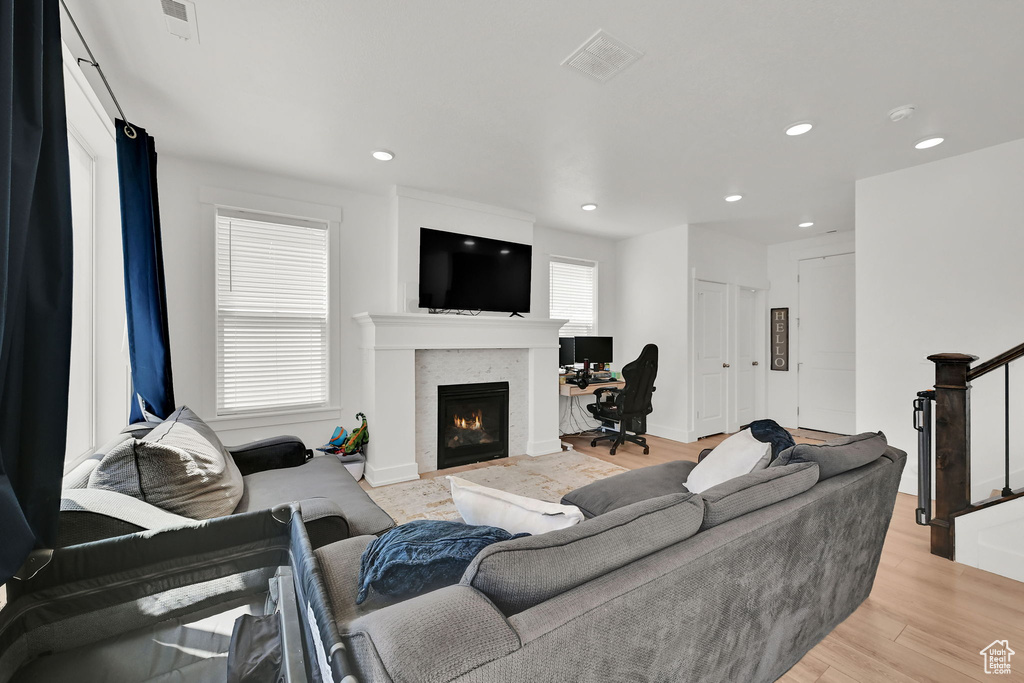 Living room featuring a lit fireplace, light wood-style flooring, and recessed lighting