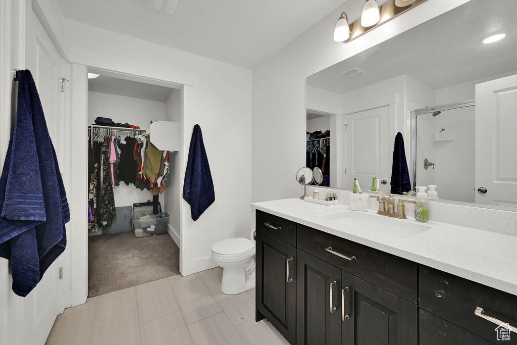 Full bath featuring a walk in closet, vanity, and a shower stall