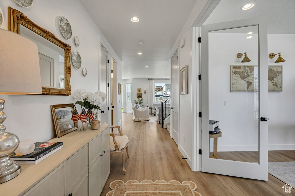 Hallway with light wood-type flooring and recessed lighting