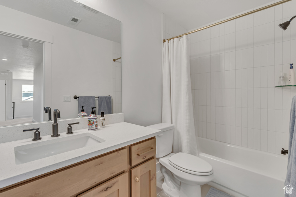 Bathroom featuring vanity and shower / bathtub combination with curtain