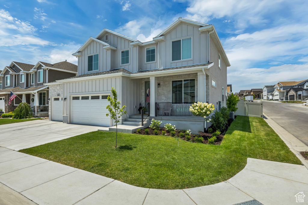 View of front of property with board and batten siding, a porch, concrete driveway, and an attached garage