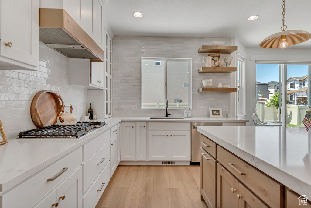 Kitchen featuring under cabinet range hood, appliances with stainless steel finishes, light wood-style flooring, decorative backsplash, and recessed lighting