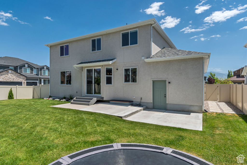 Rear view of house featuring stucco siding, a fenced backyard, a gate, and a patio area