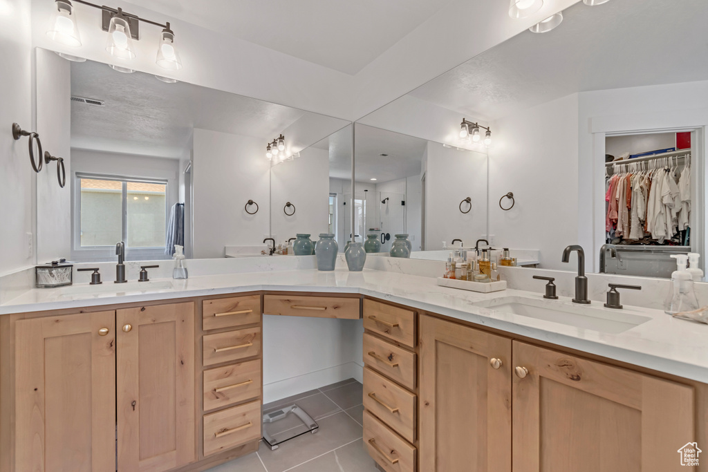 Full bath with tile patterned floors, double vanity, and a spacious closet