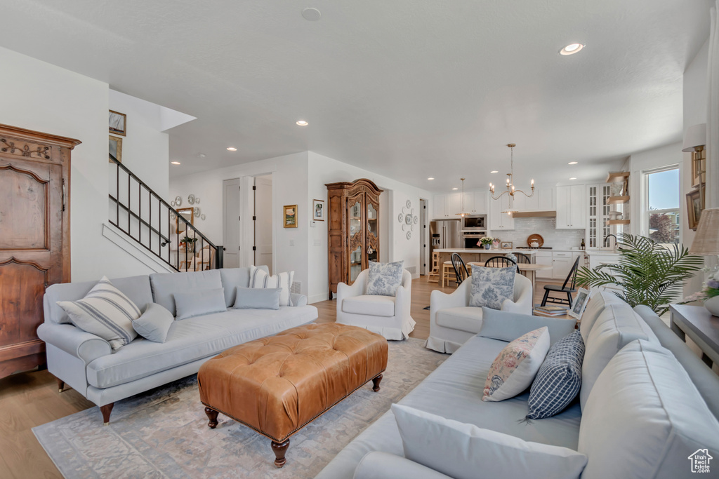 Living area featuring a chandelier, light wood-style flooring, recessed lighting, and stairs