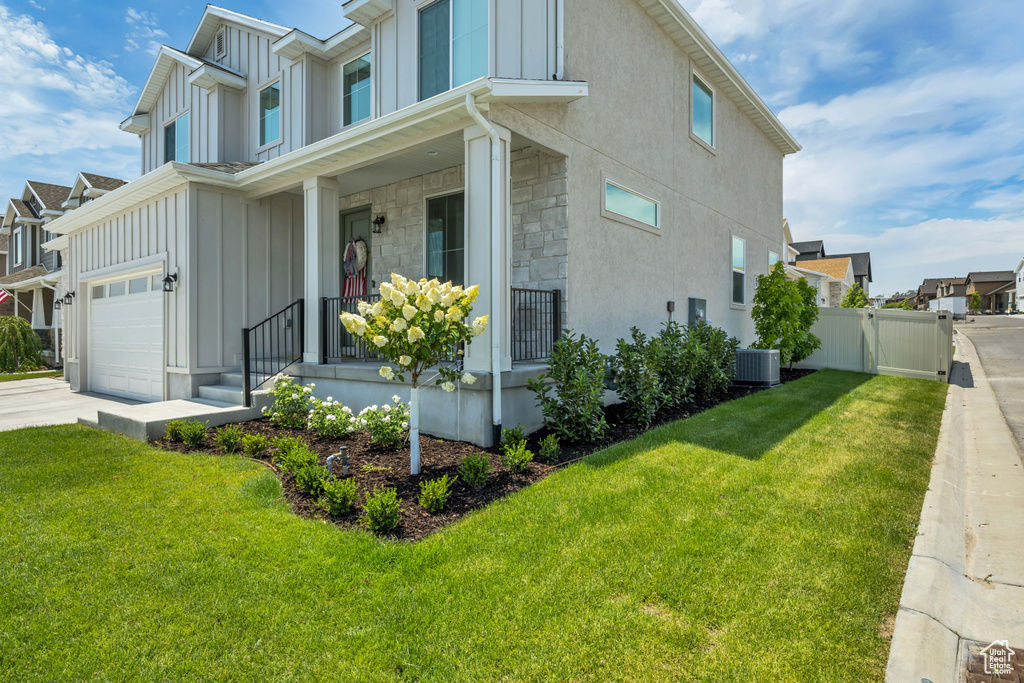 View of side of home with board and batten siding, a porch, stone siding, and concrete driveway