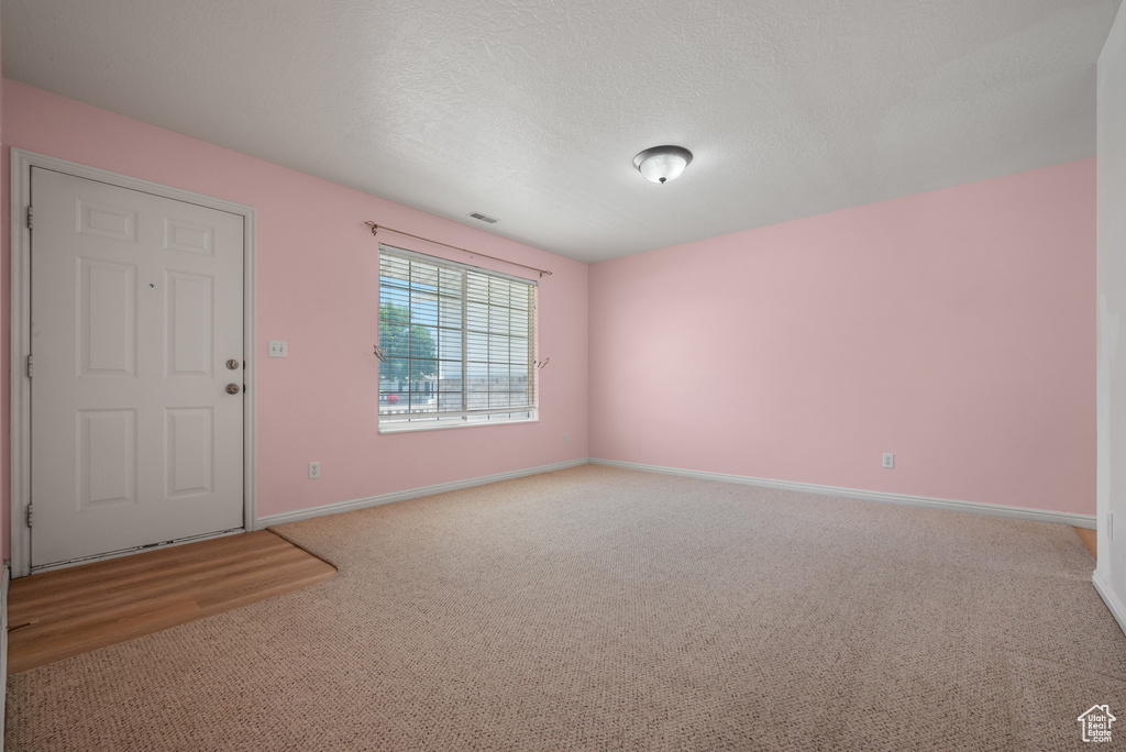 Carpeted spare room featuring baseboards