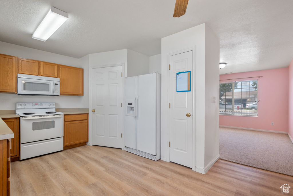 Kitchen featuring white appliances, light wood-style floors, light countertops, ceiling fan, and a textured ceiling