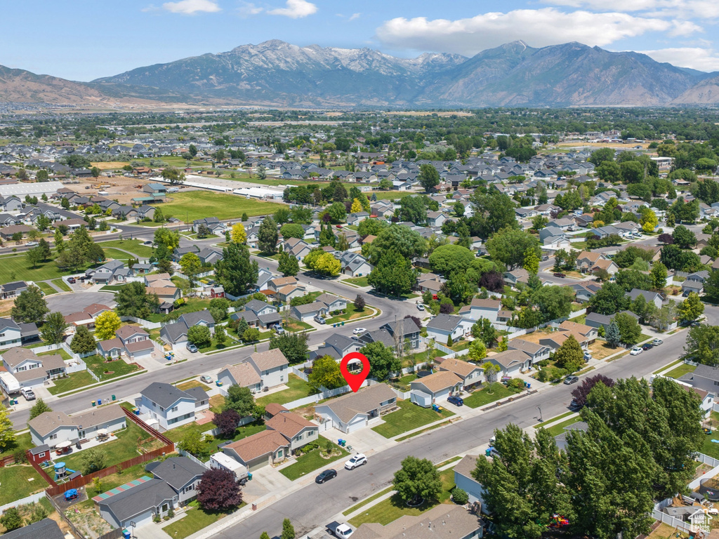 Aerial view of property and surrounding area featuring mountains and nearby suburban area