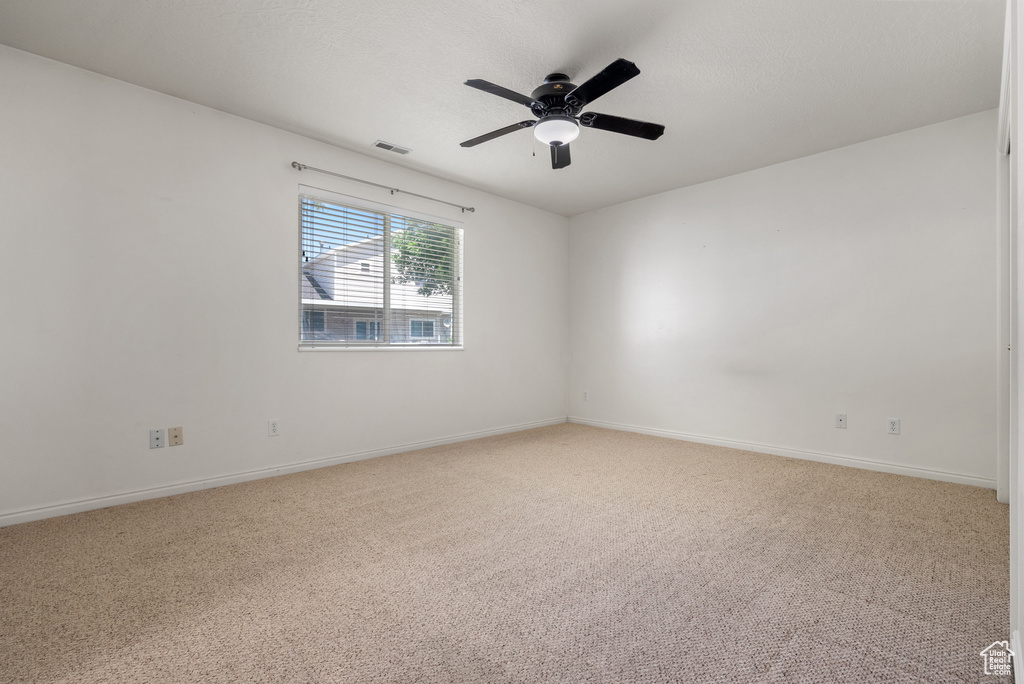Unfurnished room featuring light carpet and a ceiling fan