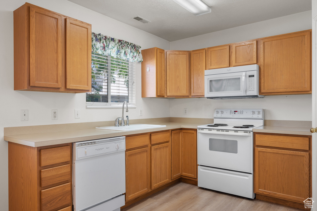 Kitchen featuring white appliances, light wood-type flooring, and light countertops