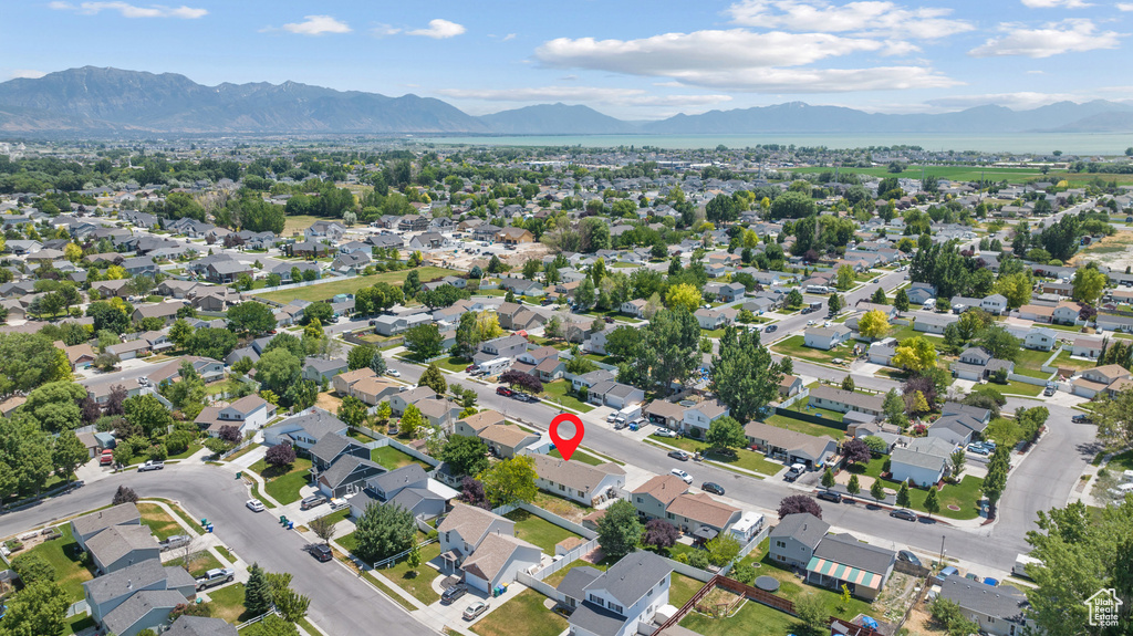Aerial view of property and surrounding area featuring a mountain backdrop and nearby suburban area