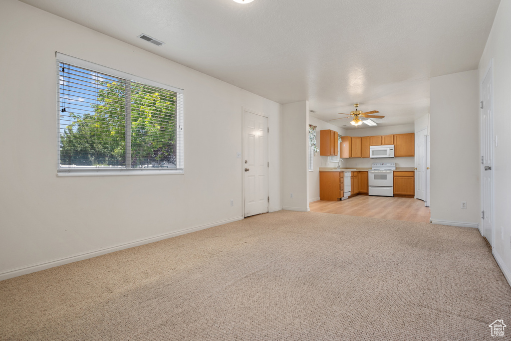 Unfurnished living room with light carpet and a ceiling fan
