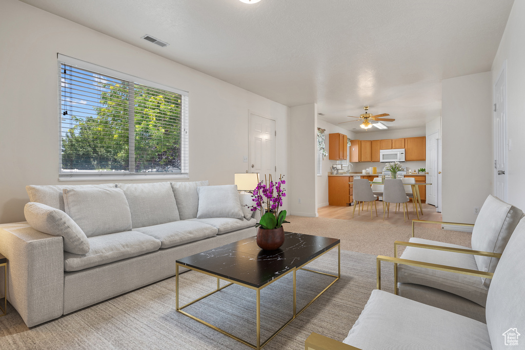 Living area with a ceiling fan and light colored carpet