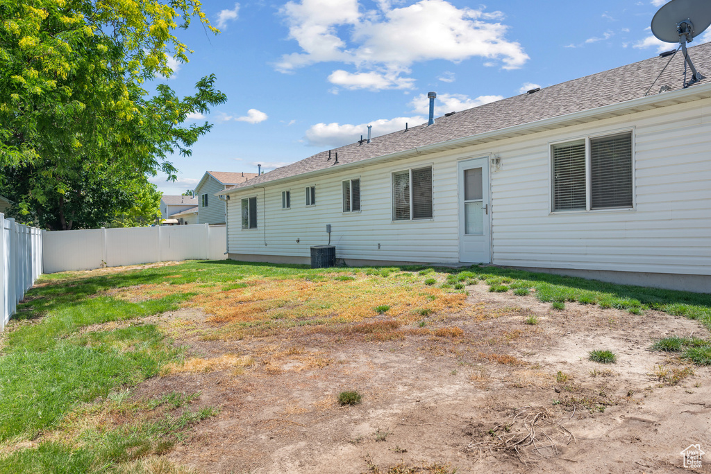 Back of house with a fenced backyard and a shingled roof