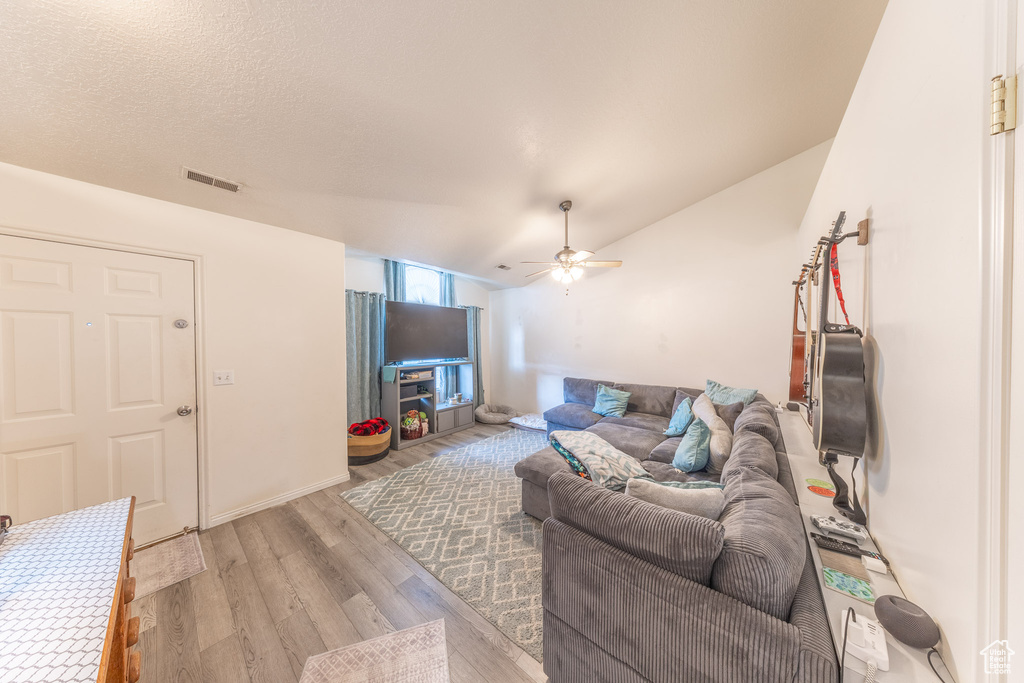 Living area with ceiling fan, light wood-style floors, and lofted ceiling