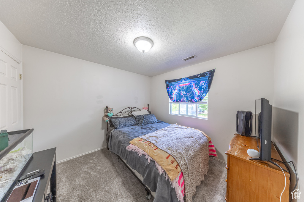 Carpeted bedroom with a textured ceiling and baseboards