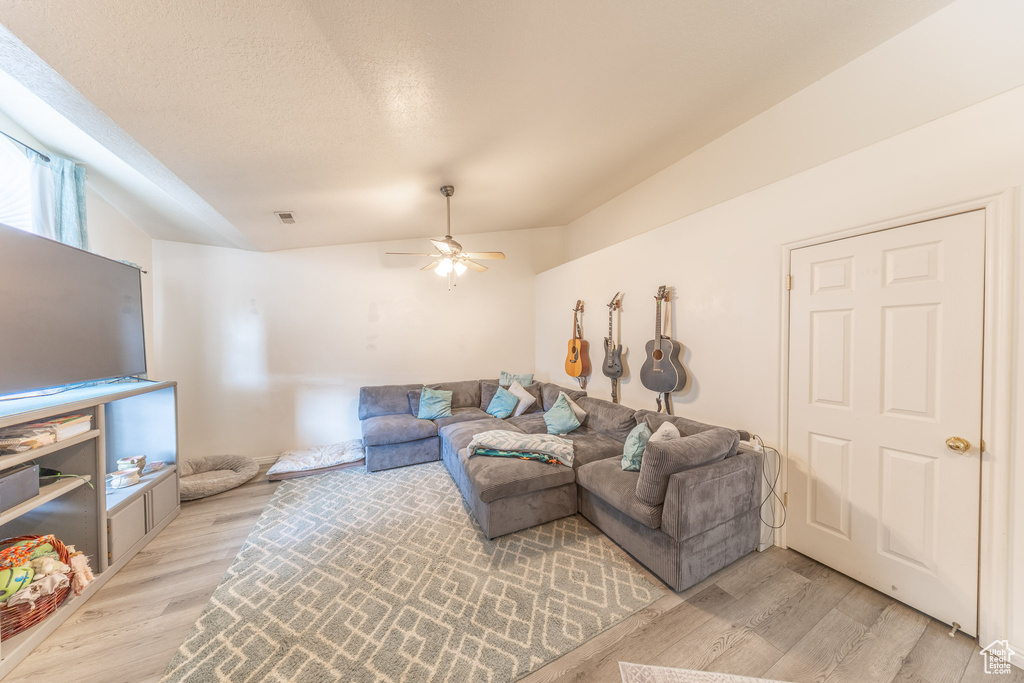 Living room featuring light wood finished floors, ceiling fan, and a textured ceiling