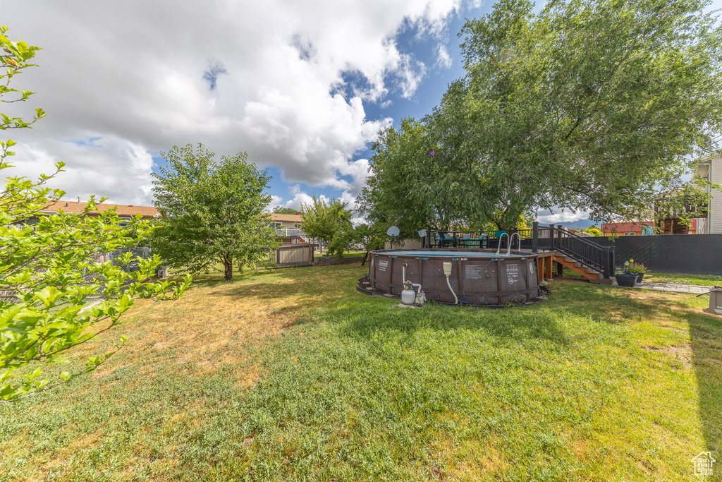 Fenced backyard with stairs, an outdoor pool, and a deck