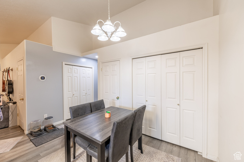 Dining room featuring a chandelier, light wood-style floors, and lofted ceiling