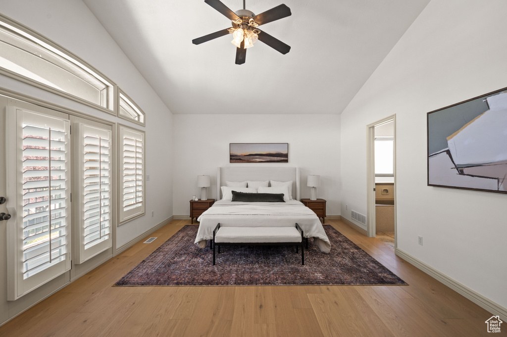 Bedroom featuring light wood-style flooring, access to outside, a ceiling fan, connected bathroom, and high vaulted ceiling