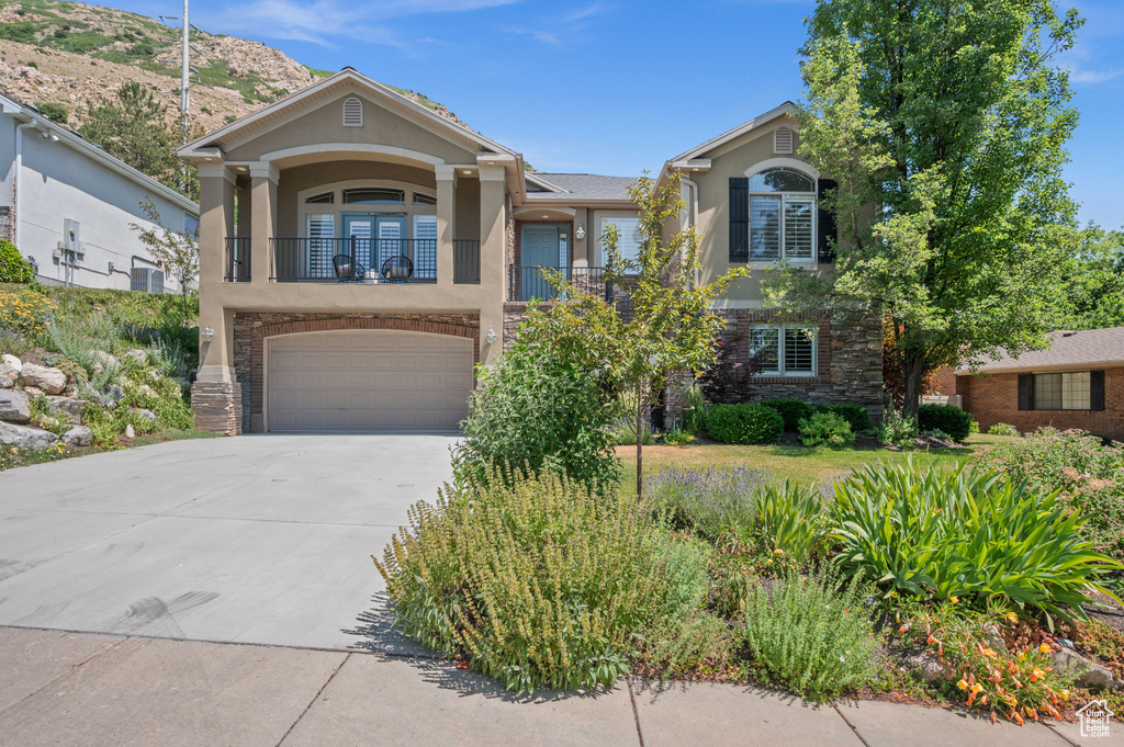 View of front of property featuring stucco siding, a balcony, driveway, and a garage